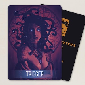 May include: A rectangular playing card featuring a dark purple and red illustration of a figure with snakes for hair and glowing blue eyes. The word TRIGGER is printed in white at the bottom. A second black card with yellow icons is partially visible.