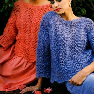 Op de afbeelding: Twee vrouwen dragen gebreide truien met een kantpatroon. De trui aan de linkerkant is koraal en de trui aan de rechterkant is blauw.