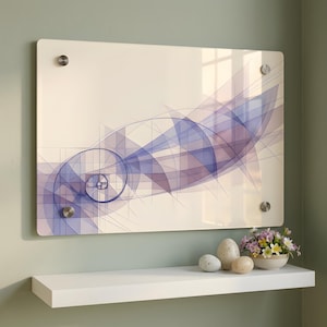 May include: A rectangular wall art piece with a cream-coloured background features a blue and purple geometric design. The artwork is mounted with four silver-coloured standoffs. A white shelf below displays decorative eggs and a small bowl of flowers.