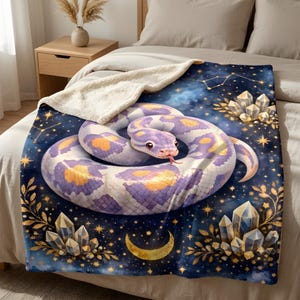 May include: A plush throw blanket featuring a coiled snake with purple and white scales and yellow spots. The background is a dark blue starry night sky with golden crescent moons, constellations, and clusters of clear, pointed crystals.