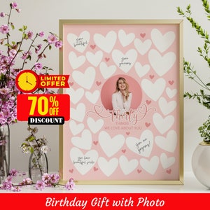 May include: A pink and white birthday sign with a photo of a person in the centre. The sign has white hearts with handwritten messages on them. The text on the sign reads "Thirty Things We Love About You".