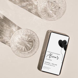 May include: A smartphone displaying a digital birthday invitation with black heart-shaped balloons. The text reads: Please join us to celebrate Alicia's 21st birthday, Saturday, May 14th, you're welcome at 8 PM, Main Street 123, Any City, RSVP 000-123-4567.