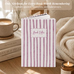 May include: A hardcover notebook featuring a white and purple vertical striped pattern. The front cover displays a scalloped rectangular label with the text "Book Notes" in a dark purple script font. The notebook is standing upright on a wooden surface.