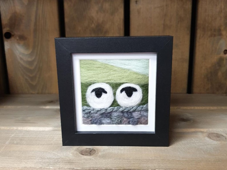 Two cute and curious sheep looking over a typical Derbyshire stone wall. Handmade needle felt picture using merino wool to give a unique wooly effect. Beautifully framed in a black frame with wall hanger. Presented with no glass to show wool fibres