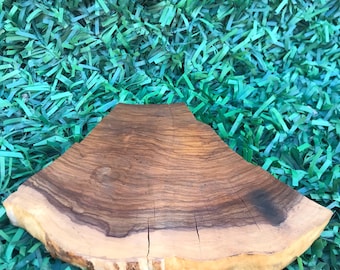 May include: A natural wood slice with a light tan outer edge and a dark brown, patterned interior. The wood has visible grain and several cracks. The background is a textured, bright green surface.
