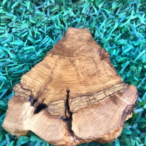 May include: A natural wood serving tray with a unique, irregular shape and a beautiful grain pattern. The tray is made from olive wood and has a warm, honey-brown color.