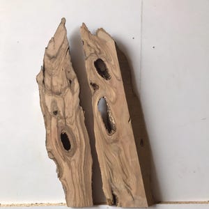May include: Two pieces of natural wood with knots and grain patterns. The wood is light brown with darker brown streaks. The pieces are about 12 inches long and 4 inches wide.