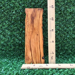 May include: A rectangular piece of natural wood with a rich, warm brown color and visible grain patterns. The wood measures approximately 9 inches in length. The text "2383" is visible on the top edge. A wooden ruler is placed next to the wood.
