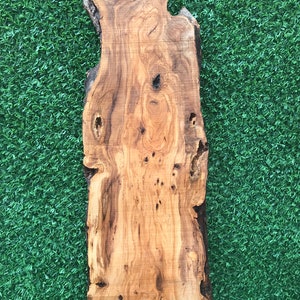 May include: A large, natural wood slab with a unique grain pattern and knots. The wood is a light brown color with darker brown streaks. The slab is perfect for crafting or woodworking projects.