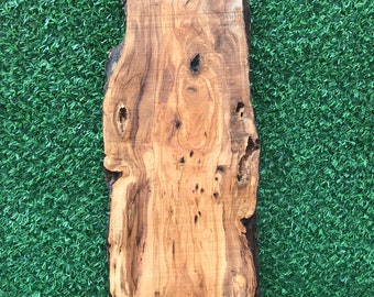 May include: A large, natural wood slab with a unique grain pattern and knots. The wood is a light brown color with darker brown streaks. The slab is perfect for crafting or woodworking projects.