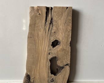 May include: A piece of wood with a natural, rustic finish. The wood has a unique grain pattern and several knots. The wood is light brown in color.
