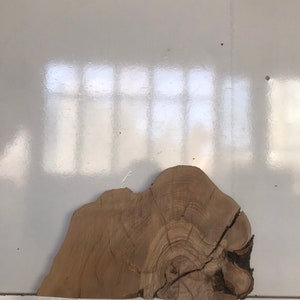 May include: A large, natural wood slice with a light brown color and a visible grain pattern. The wood slice has a rough, uneven edge and a circular shape.