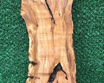 May include: A large, natural wood slab with a unique grain pattern and knots. The wood is a light brown color with darker brown streaks. The slab is smooth and polished.
