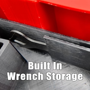 May include: Close-up of a black wrench storage compartment with a red top. The text "Built In Wrench Storage" is displayed in white. The compartment appears to be made of a 3D-printed material.