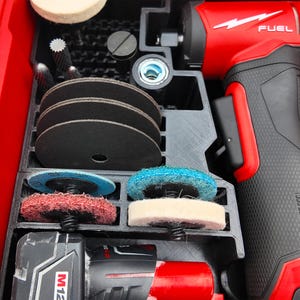 May include: A red and black power tool kit with various attachments, including sanding discs and buffing pads. The kit includes a red power drill with the word "FUEL" printed on it, and a black battery pack. The kit is organized in a black plastic case.