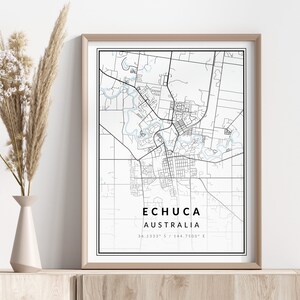 Op de afbeelding: Een zwart-witte kaartprint van Echuca, Australië, met de coördinaten 36.1333° ZB / 144.7500° OL onder de kaart. De kaart is ingelijst in een lichtbruin frame en wordt weergegeven op een lichtbruin rek.