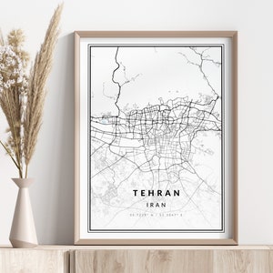 Pode incluir: Uma impressão de mapa em preto e branco de Teerã, Irã, com as coordenadas da cidade listadas abaixo. O mapa está emoldurado em uma moldura marrom clara e é exibido em uma prateleira de madeira.