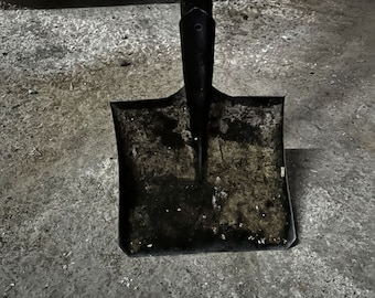 May include: A black metal shovel with a wooden handle. The shovel is dirty and has rust spots.