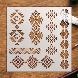 May include: A square white stencil featuring various geometric patterns, including diamond shapes, stepped borders, and repeating linear motifs. The stencil is designed for painting and crafting, with cutouts that allow for precise application of designs.