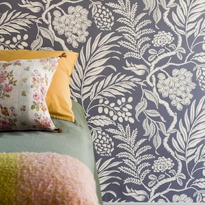 a bedroom with a blue floral wallpaper, a green bedspread, and a yellow pillow.