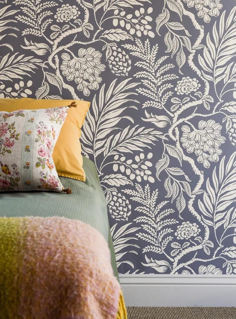 a bedroom with a blue floral wallpaper, a green bedspread, and a yellow pillow.