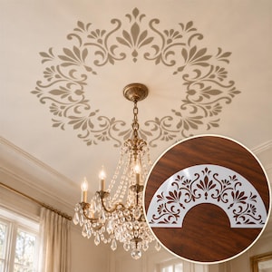 May include: A white semi-circular stencil featuring a symmetrical floral and scrollwork pattern. The stencil is shown as a cutout overlaying a ceiling medallion design painted in a muted taupe color around a crystal chandelier.