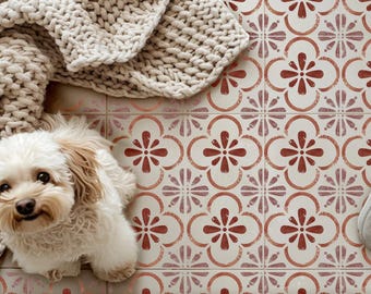 Peut inclure: Un petit chien poilu de couleur crème est assis sur un sol composé de carreaux carrés avec un motif floral répétitif de couleur terre cuite. Une couverture épaisse en tricot beige recouvre le coin supérieur gauche du carrelage.