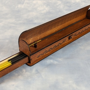 以下が含まれることがあります： 引き出し付きの木製の香炉。引き出しを開けると、お香のスティックが並んでいます。香炉には、彫刻された龍のデザインと、蝶番付きの蓋が付いています。