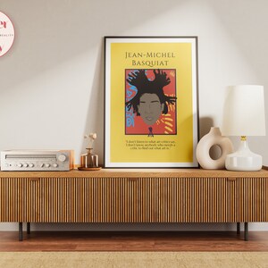 May include: A yellow poster with a portrait of Jean-Michel Basquiat, a black man with a colorful afro, against a red and yellow background. The quote "I don't listen to what art critics say. I don't know anybody who needs a critic to find out what art is." is printed below the portrait.