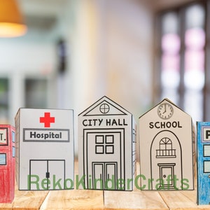 Peut inclure: Cinq b&acirc;timents en carton, chacun repr&eacute;sentant un service communautaire diff&eacute;rent&nbsp;: caserne de pompiers, h&ocirc;pital, h&ocirc;tel de ville, &eacute;cole et commissariat de police. Les b&acirc;timents sont peints de diff&eacute;rentes couleurs et pr&eacute;sentent des d&eacute;tails comme des fen&ecirc;tres, des portes et des enseignes.