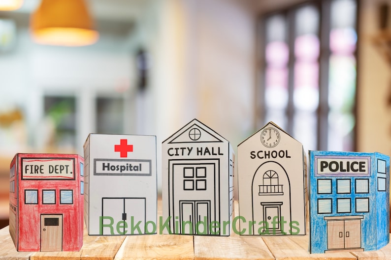 Peut inclure: Cinq b&acirc;timents en carton, chacun repr&eacute;sentant un service communautaire diff&eacute;rent&nbsp;: caserne de pompiers, h&ocirc;pital, h&ocirc;tel de ville, &eacute;cole et commissariat de police. Les b&acirc;timents sont peints de diff&eacute;rentes couleurs et pr&eacute;sentent des d&eacute;tails comme des fen&ecirc;tres, des portes et des enseignes.