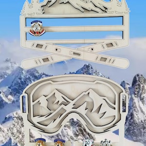 Peut inclure: Porte-épingles en bois en forme de lunettes de ski avec une scène de montagne à l'intérieur. Le porte-épingles a quatre emplacements pour les épingles. Le porte-épingles est peint dans une couleur bois clair.