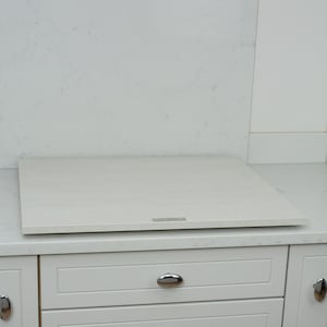 May include: White countertop with a white induction hob and white cabinets with silver hardware.