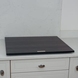 May include: A black induction hob with a sleek, modern design. The hob is installed in a white kitchen worktop.