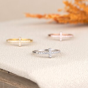 Pu&ograve; includere: Tre anelli delicati con un design a croce incastonati con piccole pietre scintillanti. Gli anelli sono in oro, oro rosa e argento.