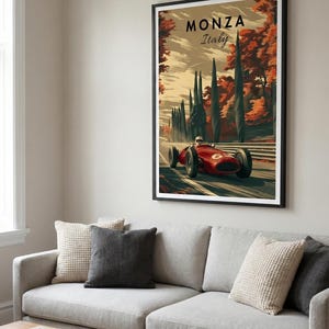 May include: A framed art print featuring a vintage race car speeding on a track. The artwork, titled "Monza Italy," showcases a red race car against a backdrop of autumn trees. The print is displayed above a gray sofa with decorative pillows.
