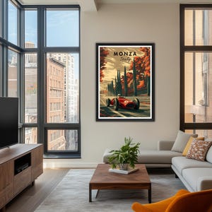 May include: Framed Monza Italy vintage racing poster. The artwork features a red race car speeding along a track, with the text "Monza Italy" at the top. The background includes trees and a sunset sky. The poster is displayed in a modern living room.