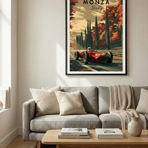 May include: A framed art print featuring a vintage race car speeding along a tree-lined road in Monza, Italy. The artwork has a retro style with a red race car and the text "MONZA Italy". The print is displayed above a gray sofa.