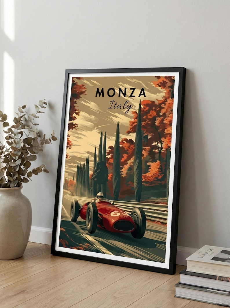 May include: A framed poster depicting a vintage red racing car on a track in Monza, Italy. The artwork has a retro style with the text "Monza Italy" at the top. The background features tall trees and autumn foliage.