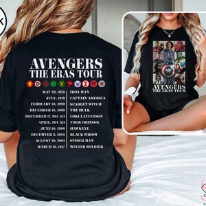 Może przedstawiać: Czarny T-shirt z białym nadrukiem logo Avengers i tekstem "Avengers The Eras Tour". Grafika zawiera daty i nazwiska każdego z Avengers&oacute;w, w tym Iron Mana, Kapitana Amerykę, Szkarłatną Wiedźmę, Hulka, Lokiego Laufeysona, Thora Odison, Hawkeye, Czarną Wdowę, Spider-Mana i Zimowego Żołnierza.