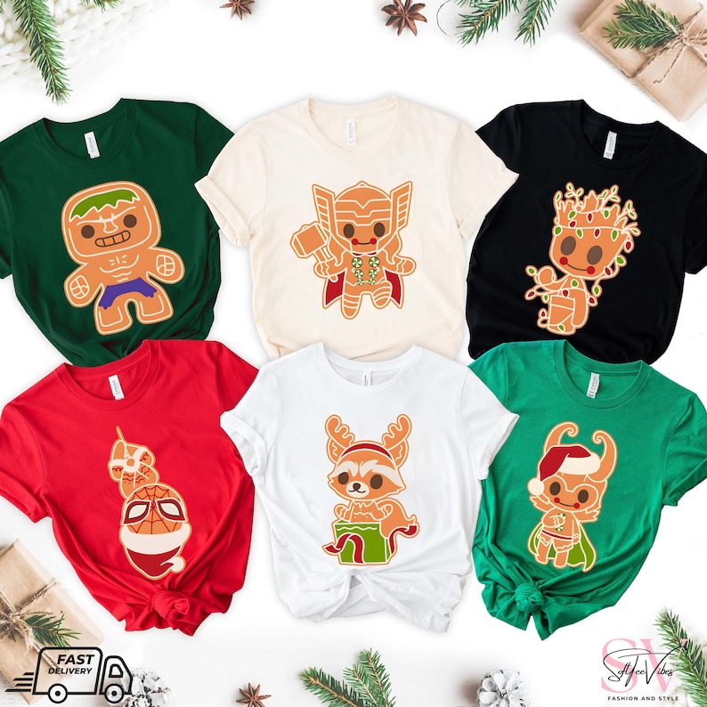 May include: Six different t-shirts featuring various Marvel characters as gingerbread cookies. The characters include Hulk, Thor, Groot, Rocket Raccoon, and Spider-Man. The shirts are in various colors, including green, beige, black, red, and white.