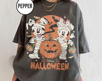 May include: Dark gray t-shirt featuring a Halloween design with Mickey and Minnie Mouse dressed as mummies, a carved pumpkin, and the text "Disney Halloween". The design includes bats, stars, and a ghost.