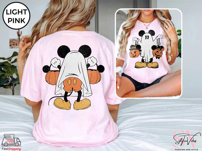 Puede incluir: Una camiseta rosa claro con un gr&aacute;fico de Mickey Mouse disfrazado de fantasma sosteniendo calabazas. El gr&aacute;fico est&aacute; en la parte posterior de la camiseta.