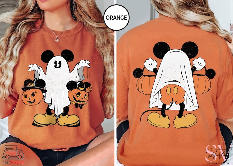 Puede incluir: Camiseta naranja con un personaje de Mickey Mouse disfrazado de fantasma sosteniendo dos calabazas de jack-o'-lantern. La parte posterior de la camiseta presenta a Mickey Mouse disfrazado de fantasma de espaldas al espectador.