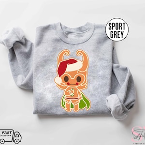 May include: A gray sweatshirt with a Christmas-themed illustration of a gingerbread person wearing a Santa hat and holding a candy cane. The gingerbread person is wearing a green cape and has a red and white striped candy cane.