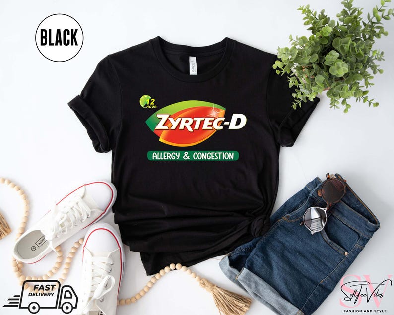 May include: Black t-shirt with the text "ZYRTEC-D ALLERGY & CONGESTION" in green, red, and white. The shirt is styled with white sneakers, blue denim shorts, and sunglasses. A small plant and a beaded necklace are also in the image.