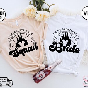 Puede incluir: Dos camisetas con un gráfico en blanco y negro del castillo de Cenicienta con orejas de Mickey Mouse. El texto en las camisetas dice "Bachelorette Bash Squad" y "It's My Bachelorette Bride".
