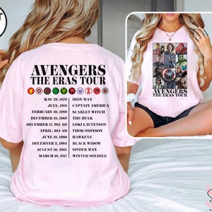 Może przedstawiać: R&oacute;żowy T-shirt z napisem "Avengers The Eras Tour" i listą postaci Avengers wraz z datami ich pierwszych pojawień się. Postacie to Iron Man, Captain America, Scarlet Witch, Hulk, Loki Laufeyson, Thor Odinson, Hawkeye, Black Widow, Spider-Man i Winter Soldier.