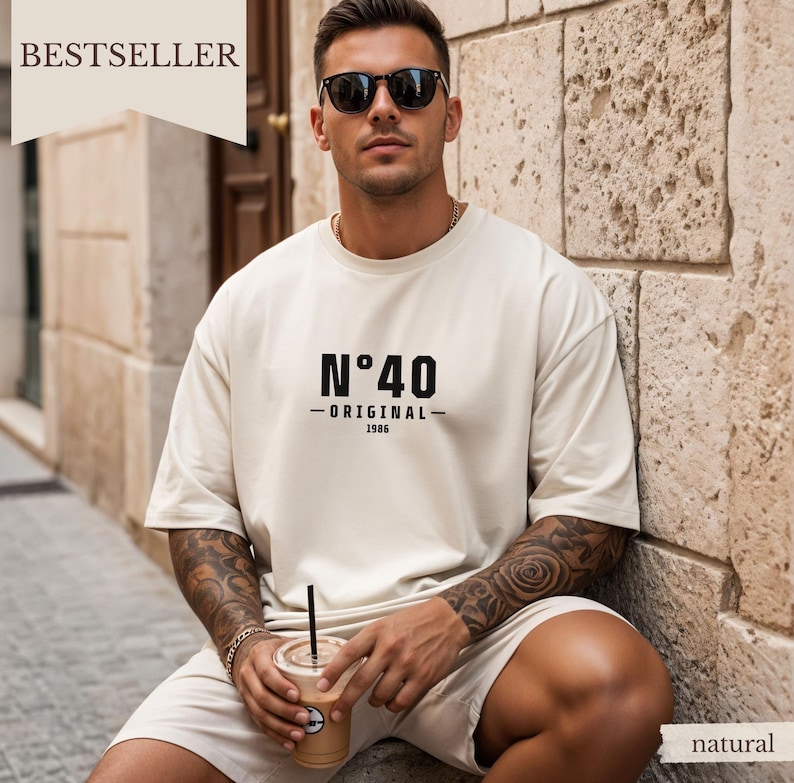 May include: An off-white short-sleeve t-shirt featuring the black text N&deg;40 ORIGINAL 1986 printed on the chest. The shirt has a crew neckline and a relaxed fit, paired with matching off-white shorts. The design is simple and features bold typography.