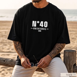 May include: A black short-sleeved t-shirt featuring white text on the chest that reads N&deg;40 ORIGINAL 1986. The shirt has a crew neckline and a loose, relaxed fit. The design is centered on the front of the garment in a clean, bold font.